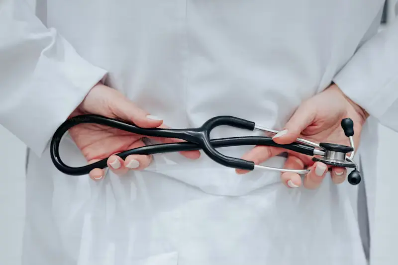 A healthcare professional holding a stethoscope behind their back
