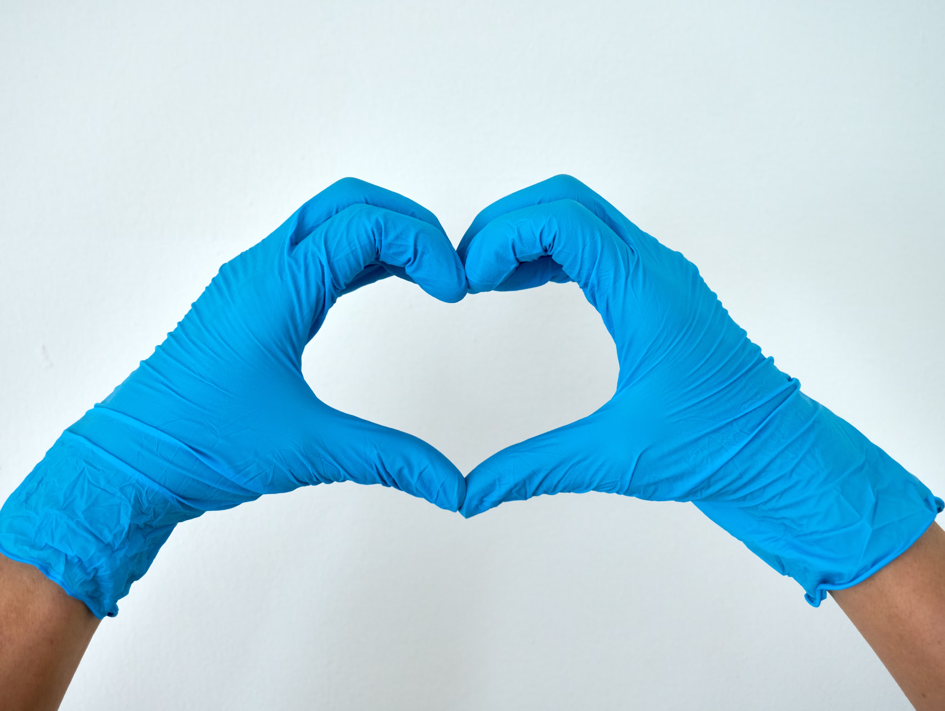Gloved hands forming a heart, a symbol of care