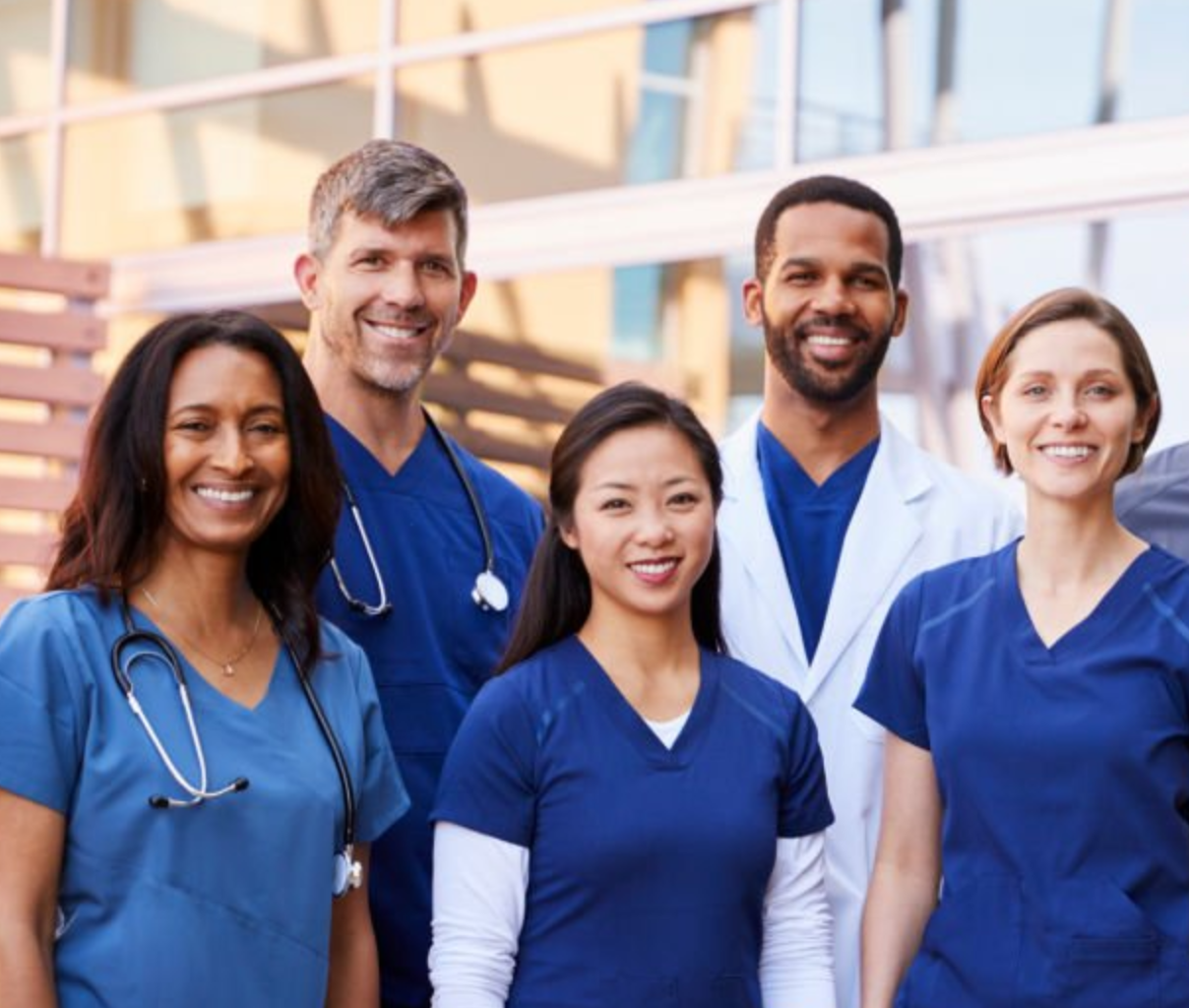 A diverse team of clinicians standing together outside a modern clinic